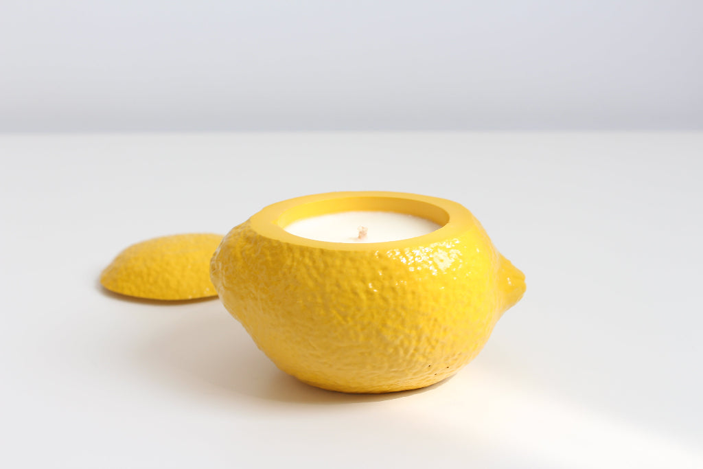 Yellow lemon-shaped candle on a white background