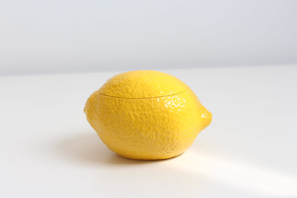 Yellow ceramic lemon-shaped container candle on a white background