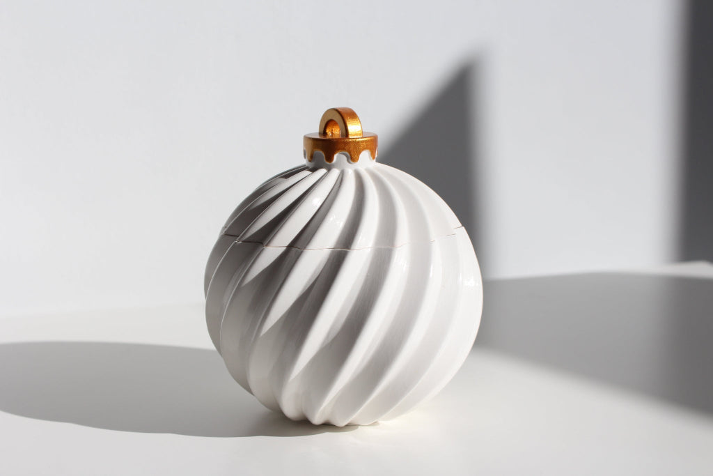 White ceramic ornament candle with gold top on a light gray background