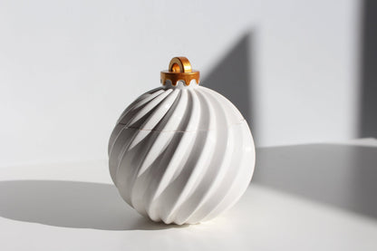 White ceramic ornament candle with gold top on a light gray background